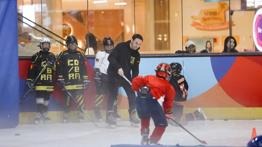 A coach working with players along the boards